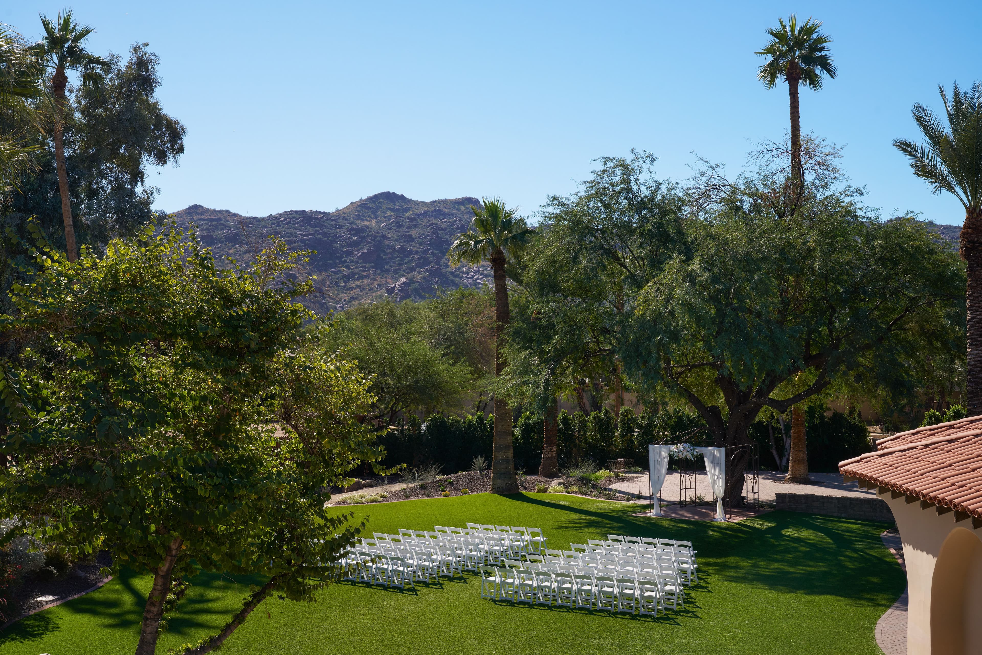 Outdoor wedding reception with white and gold tables surrounded by lush greenery at Secret Garden by Wedgewood Weddings.