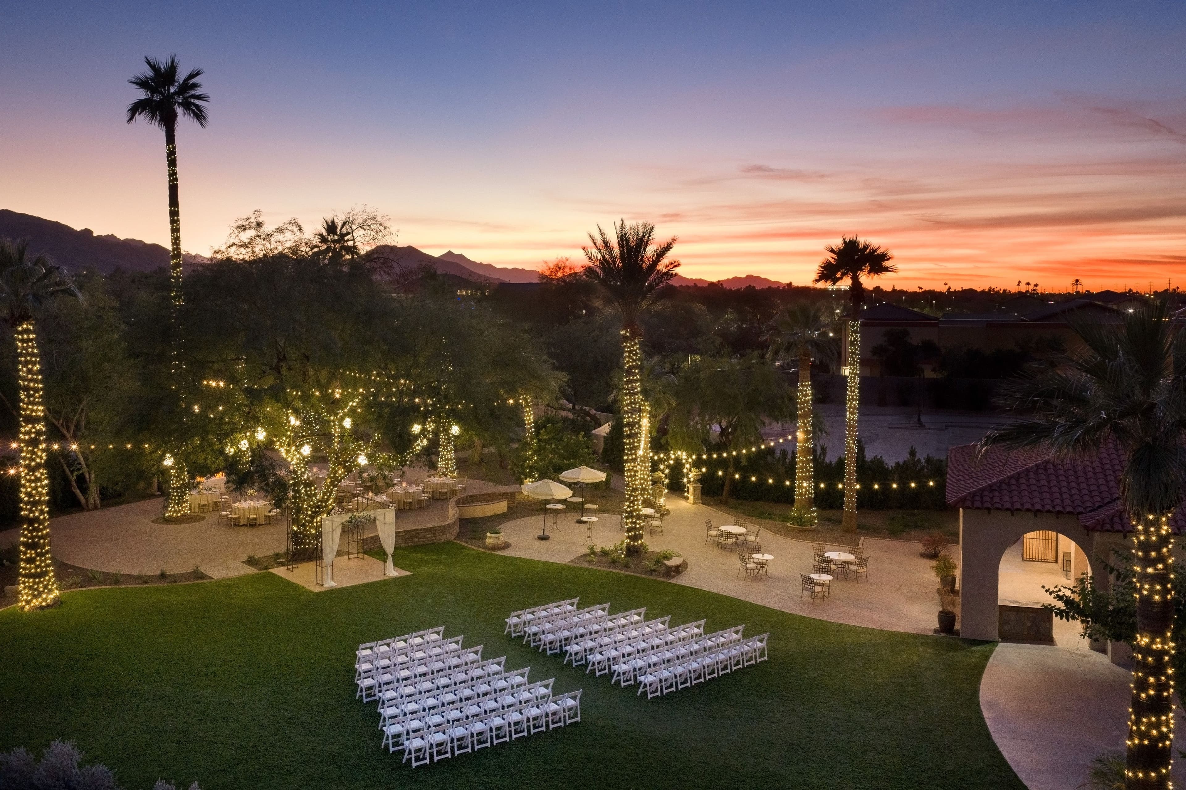 An Arizona sunset and bistro lights light up the ceremony lawn at Secret Garden by Wedgewood Weddings.